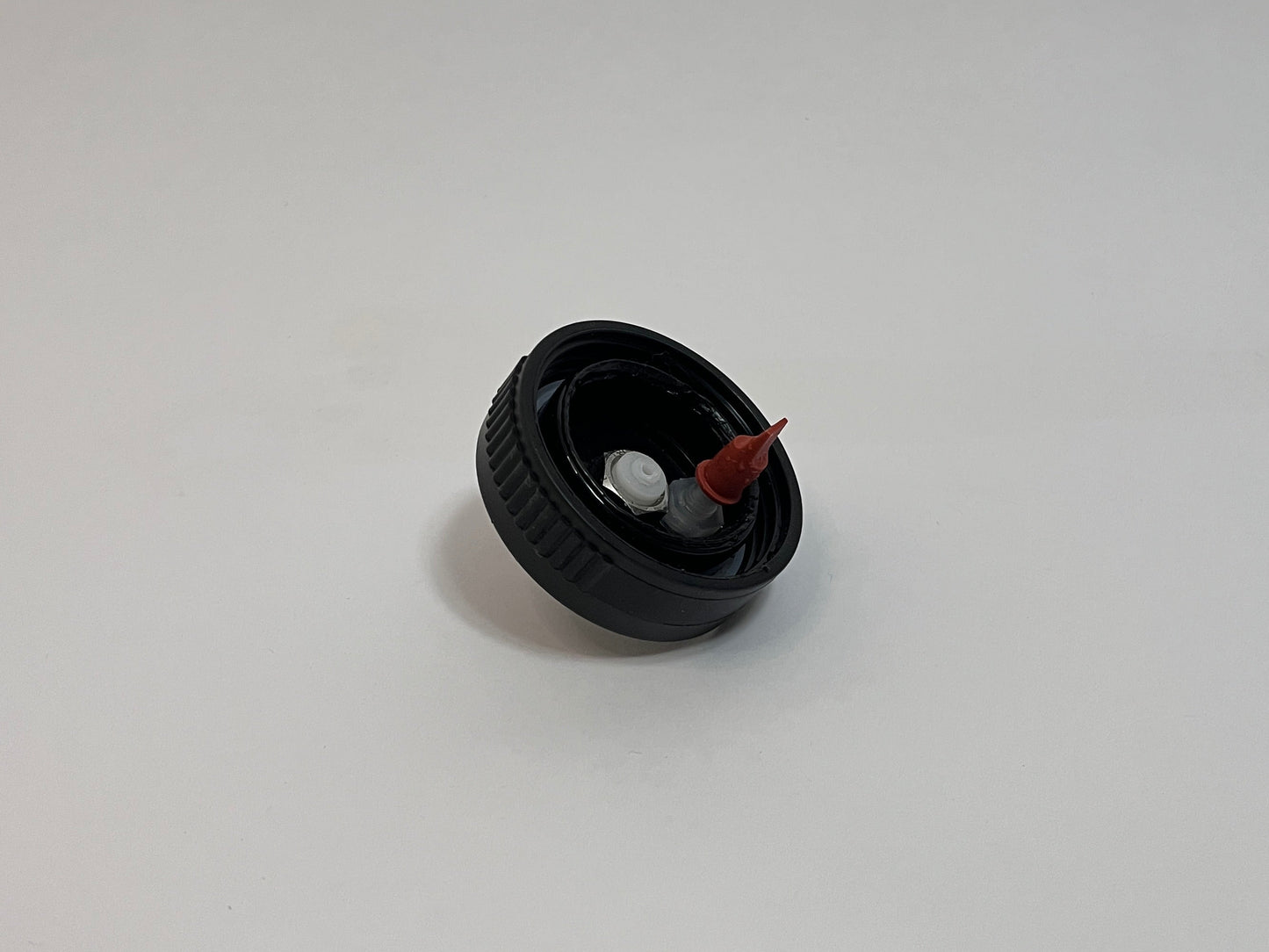CPC cap showing the inside of the cap with white cpc fitting and red duckbill valve on a white background