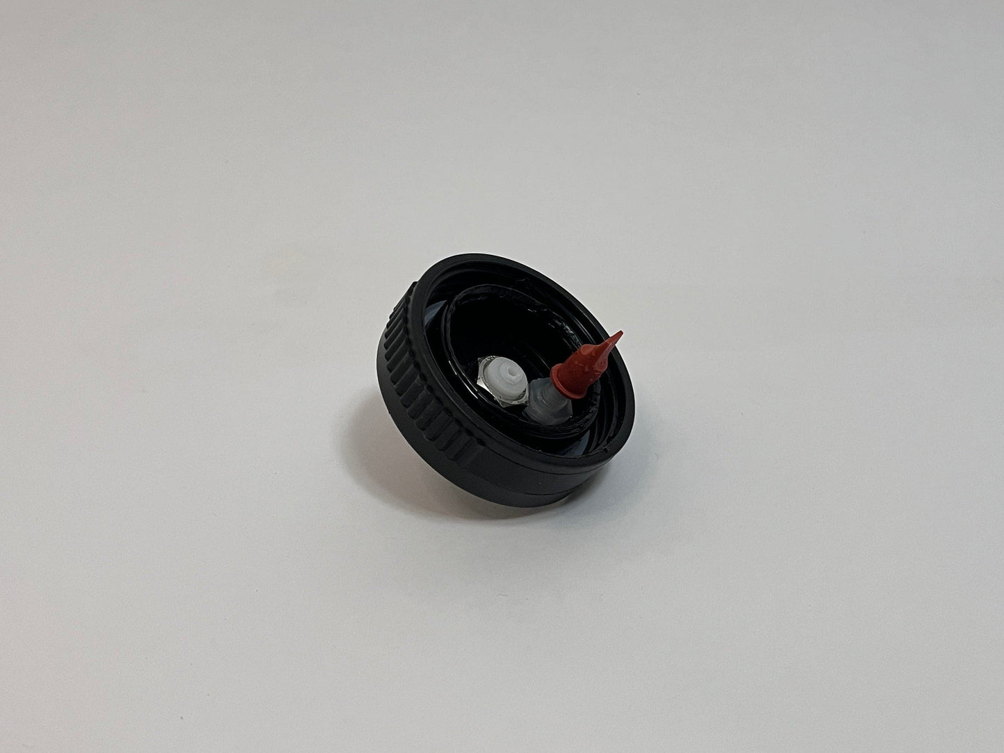 CPC cap showing the inside of the cap with white cpc fitting and red duckbill valve on a white background