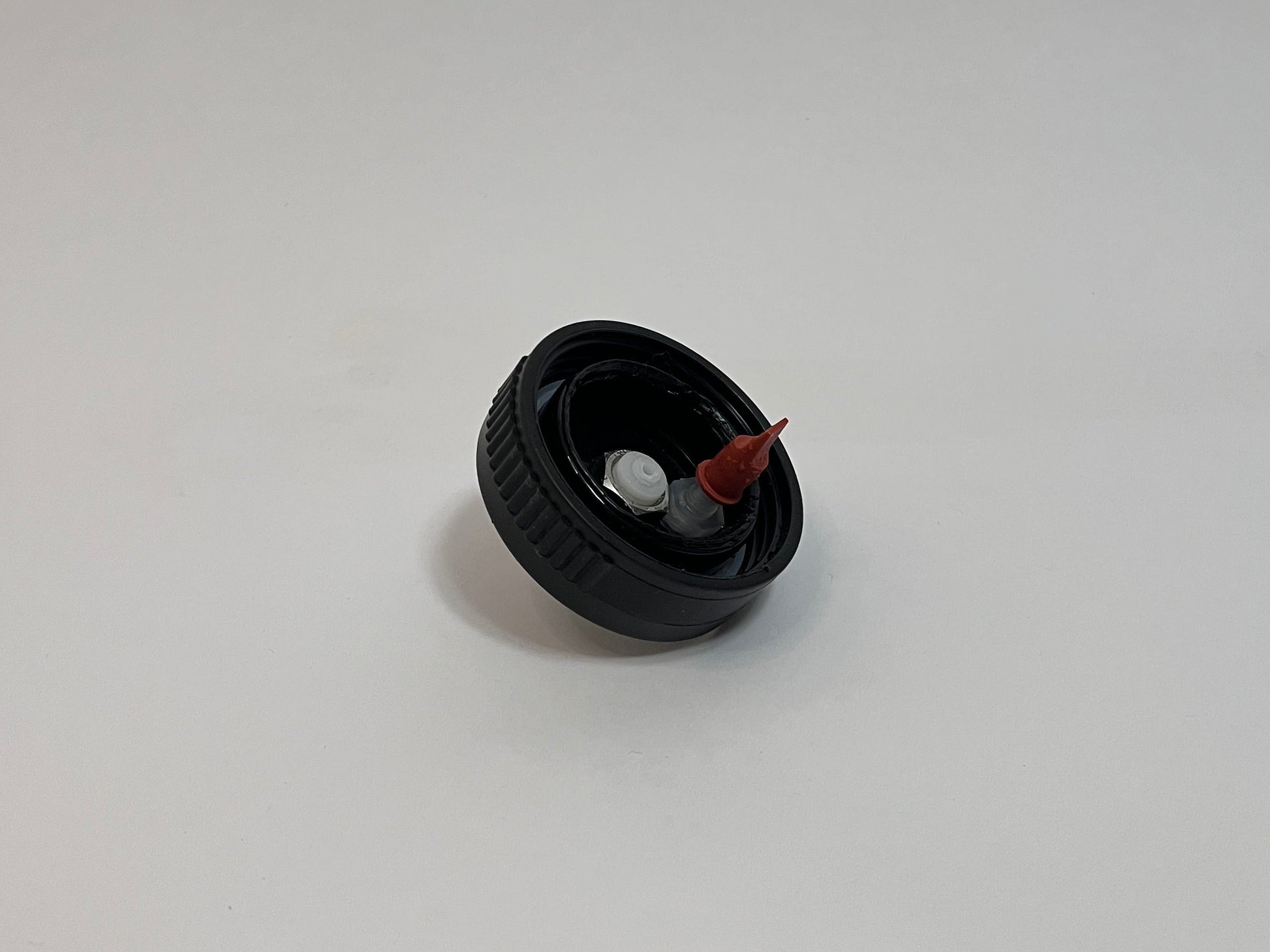CPC cap showing the inside of the cap with white cpc fitting and red duckbill valve on a white background