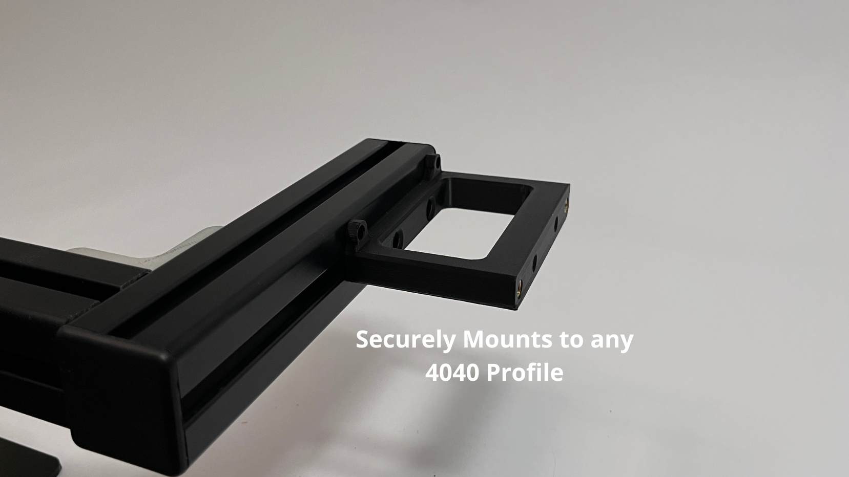 A close-up of a black Plastic button box mount showing its connection point with overlaid text that reads 'Securely Mounts to any 4040 Profile' on a light gray background.